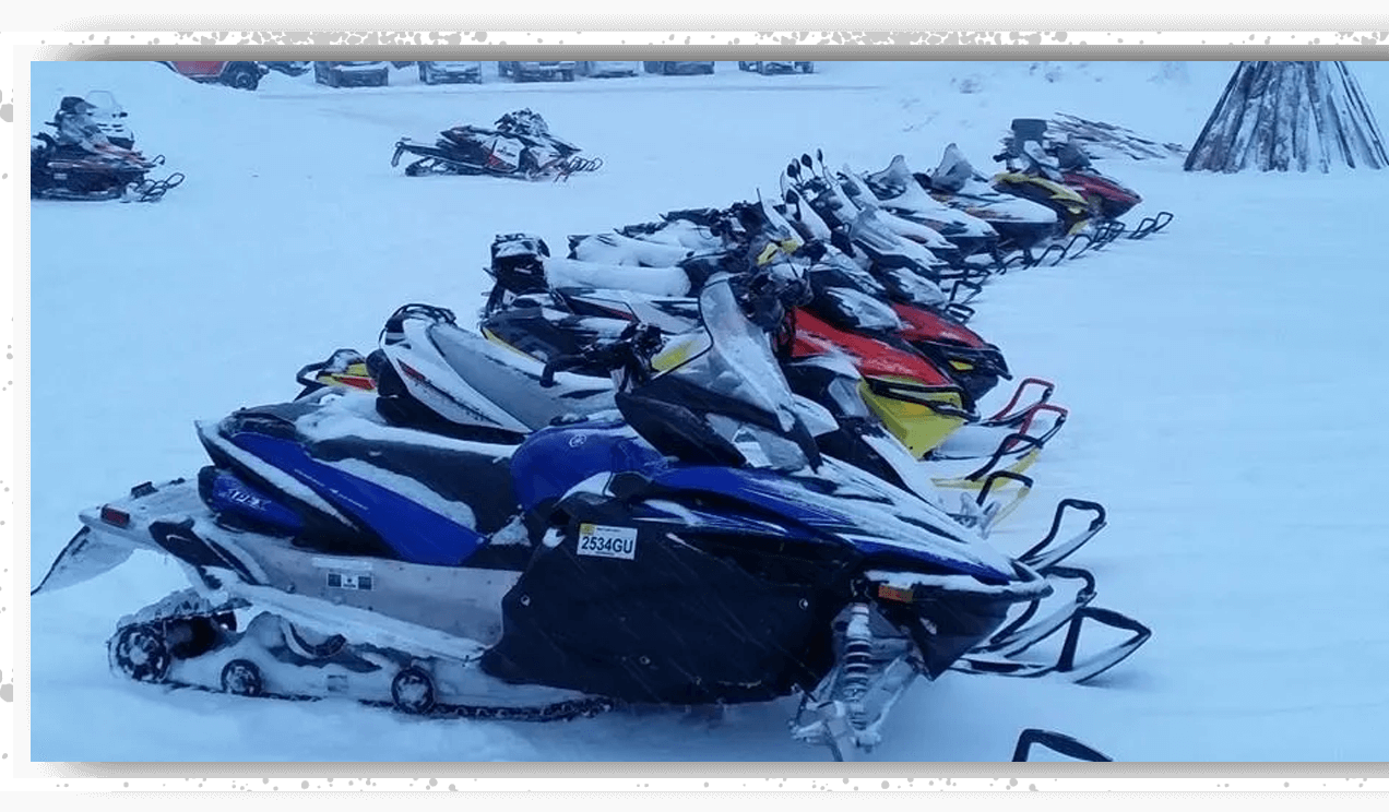 A bunch of snowmobiles are parked in the snow