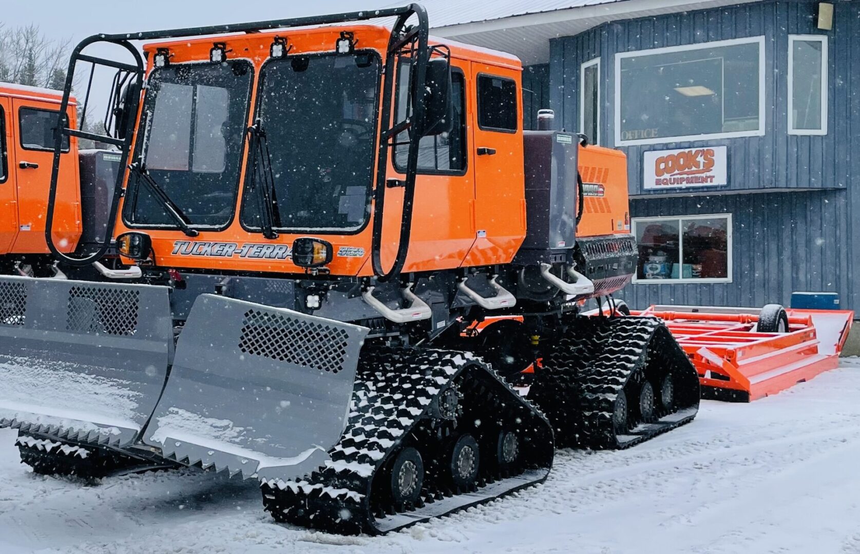 A large orange snow plow truck parked in the street.