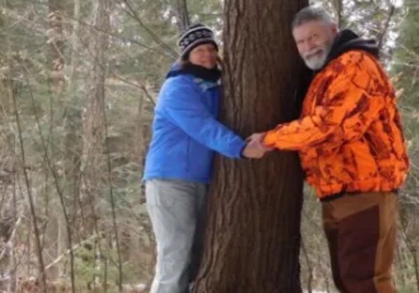 A man and woman holding hands next to a tree.